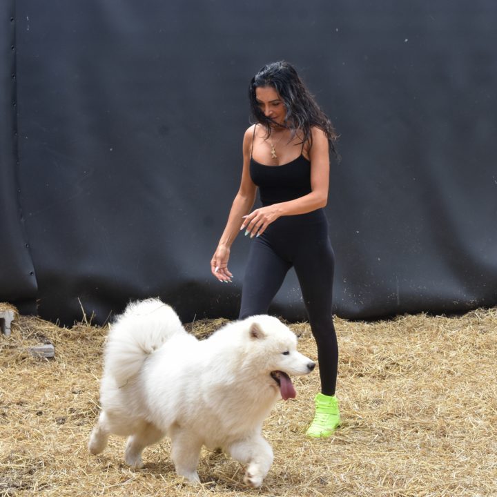 Woman walking with fluffy white dog outdoors.