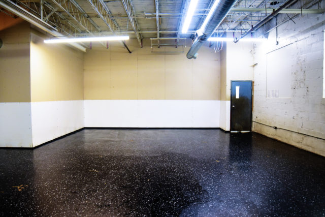 Empty industrial room with concrete floor and lighting.