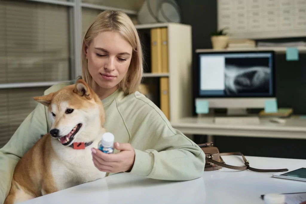 staff reading label on dog medication with a dog on their lap